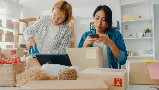 Young Asia businesswomen using mobile phone call receiving purchase order and check product on stock work at home office. Small business owner, online market delivery, lifestyle freelance concept.