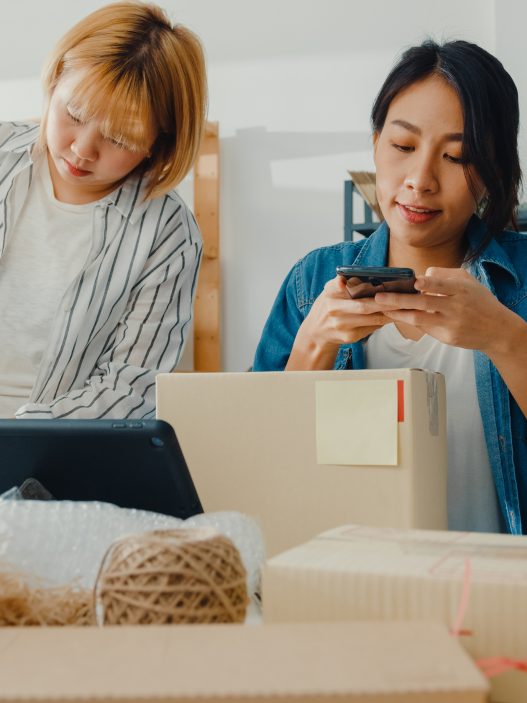 Young Asia businesswomen using mobile phone call receiving purchase order and check product on stock work at home office. Small business owner, online market delivery, lifestyle freelance concept.